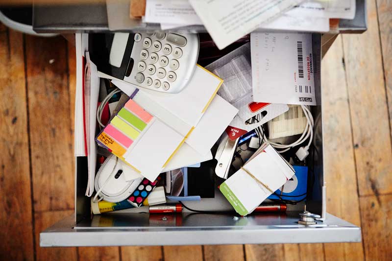 A messy kitchen junk drawer filled with tangled cords, old keys, and forgotten items — representing the hidden clutter in your business technology